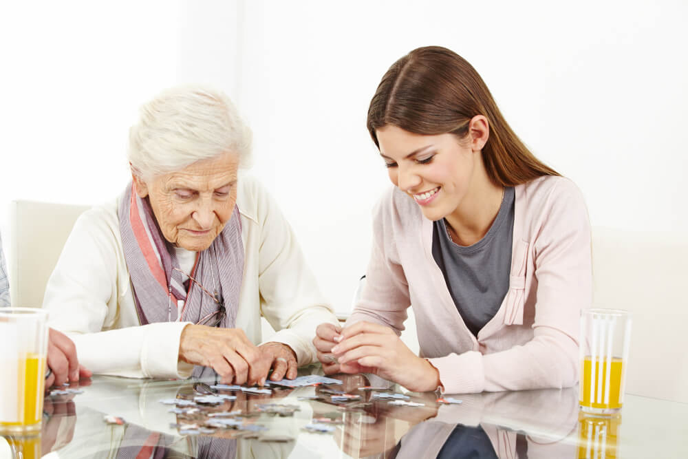 young lady playing puzzle with a senior woman