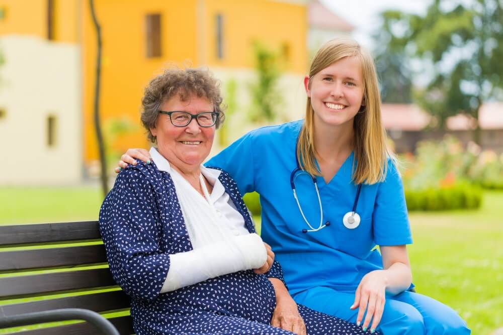 nurse and a senior woman sitting on a bench